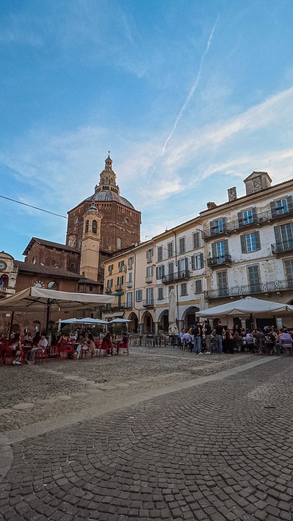 Piazza della Vittoria de Pavia avec ses arcades et terrasses et coupole du Duomo en fond, Italie